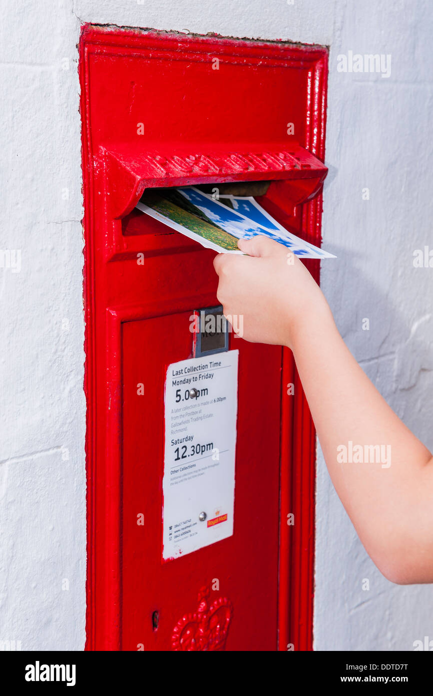 Ein Junge von 9, die Entsendung einer Postkarte in einer Royal Mail-Briefkasten im Vereinigten Königreich Stockfoto