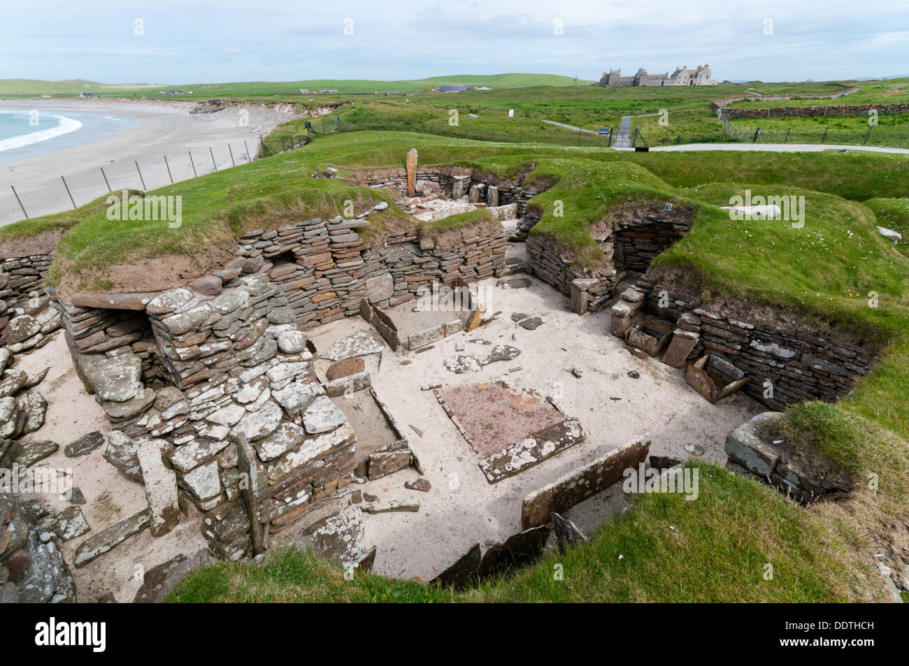 Haus 5 in Skara Brae neolithischen Dorf auf Orkney Festland mit Skaill Bay und Skaill House im Hintergrund. Stockfoto