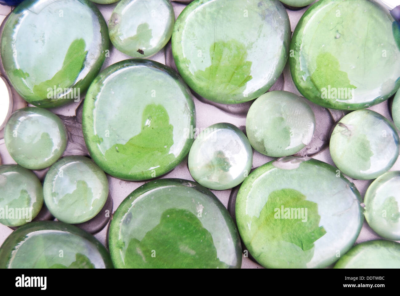 Grüne glänzende Kieselsteine, alle nebeneinander. Stockfoto