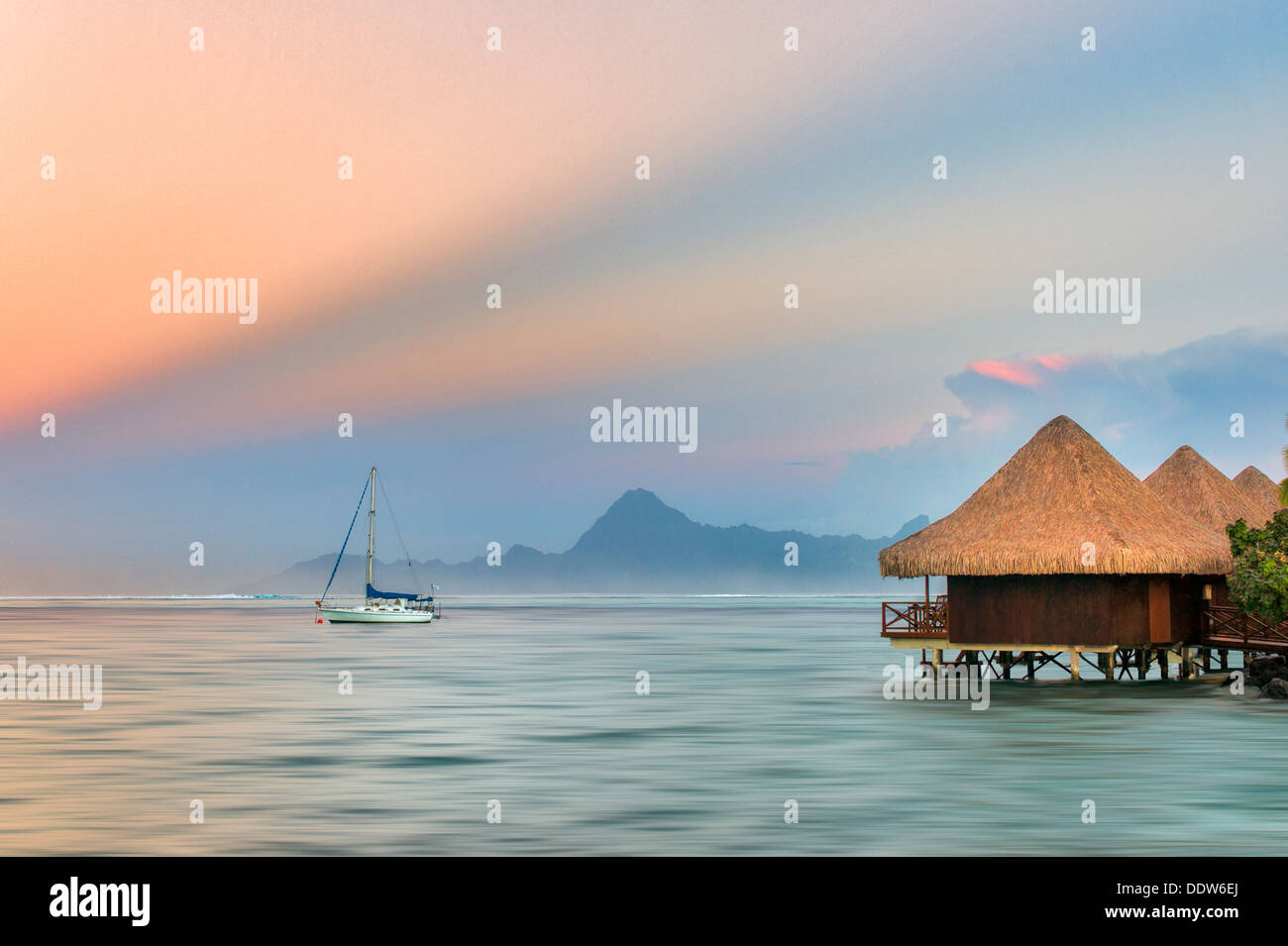 Die Bungalows über dem Wasser mit einem Segelboot und Sonnenaufgang und Moorea, Tahiti Stockfoto