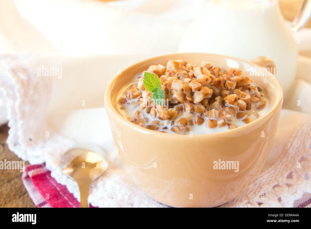 Buchweizengrütze mit Milch und Minze auf Holztisch, Nahaufnahme, horizontale. Natürliche Bio vegetarisches Essen (Frühstück). Stockfoto