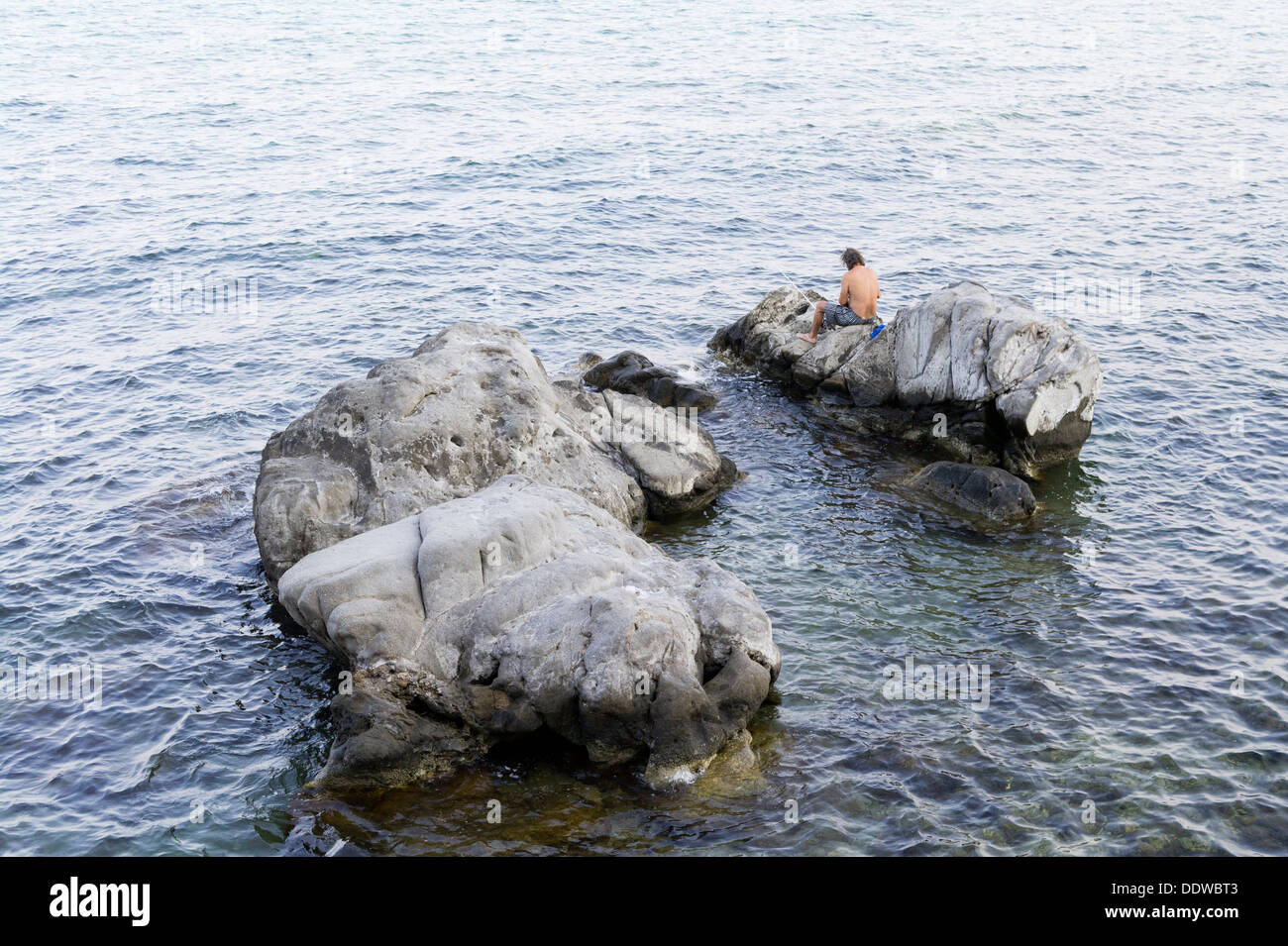 Mann Angeln im Meer von Felsen Giardini Naxos Sizilien Stockfoto