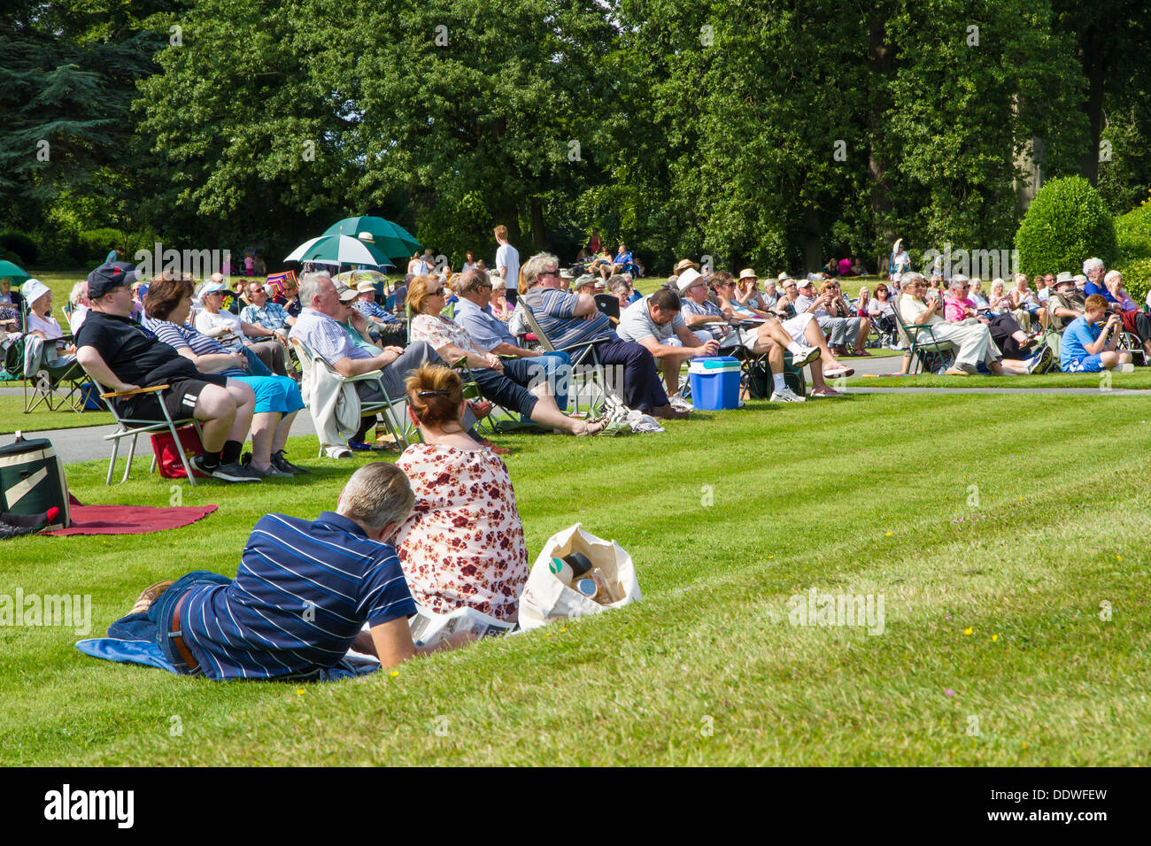 Besucher nach Brodsworth Hall in Doncaster saß auf dem Rasen in der Sonne am Nachmittag Band Konzert anhören. Stockfoto