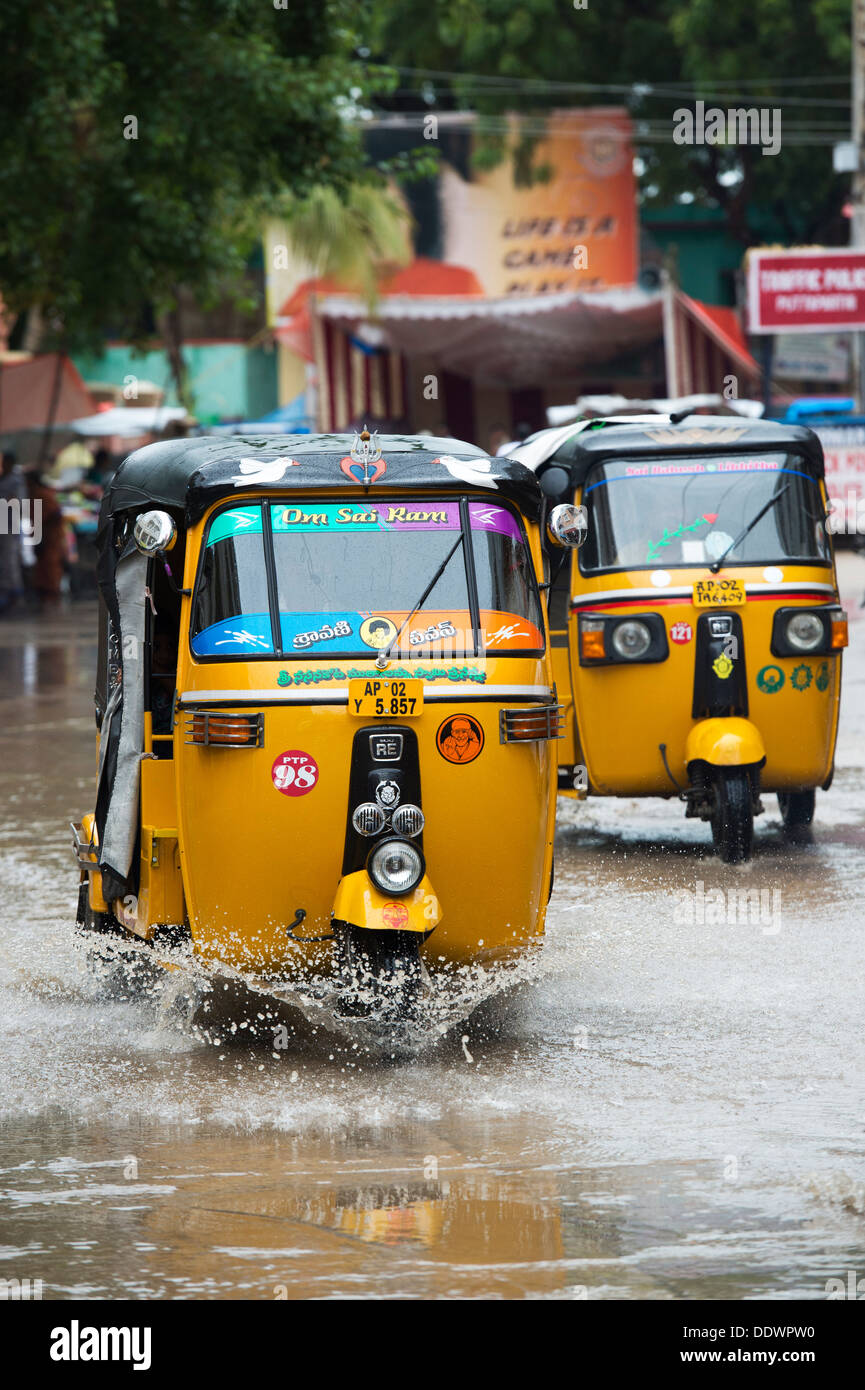 Indische Auto-Rikschas fahren durch nasse Straßen in Puttaparthi, Andhra Pradesh, Indien Stockfoto