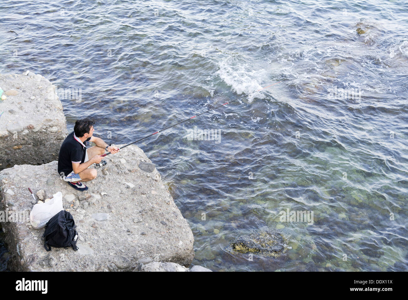 Mann Angeln im Meer von Felsen Giardini Naxos Sizilien Stockfoto