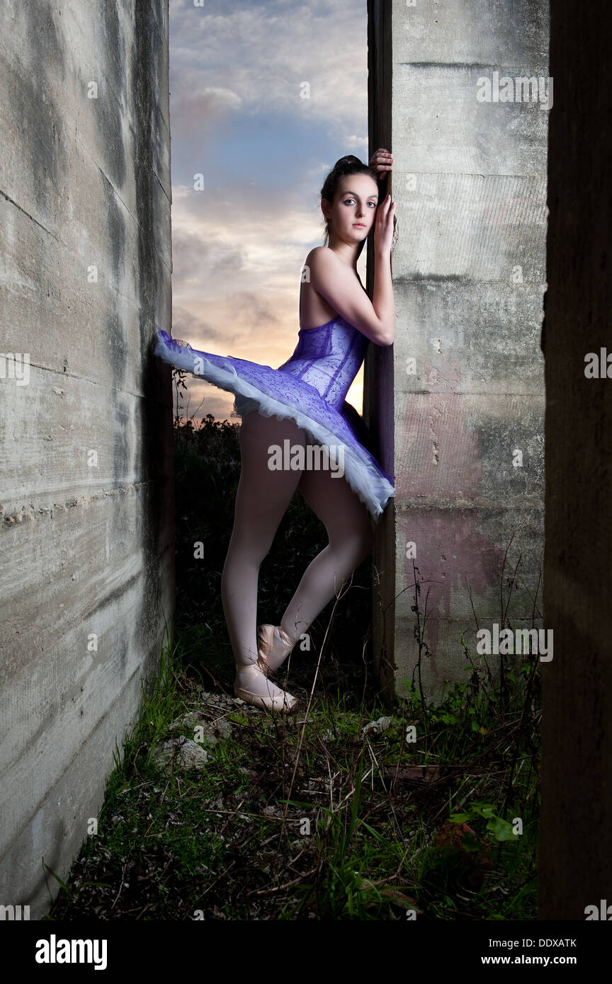 Ballerina posiert in einem alten verfallenen Gebäude während der letzten Stunde des Sonnenlichts und wenn die Sonne untergeht. Stockfoto