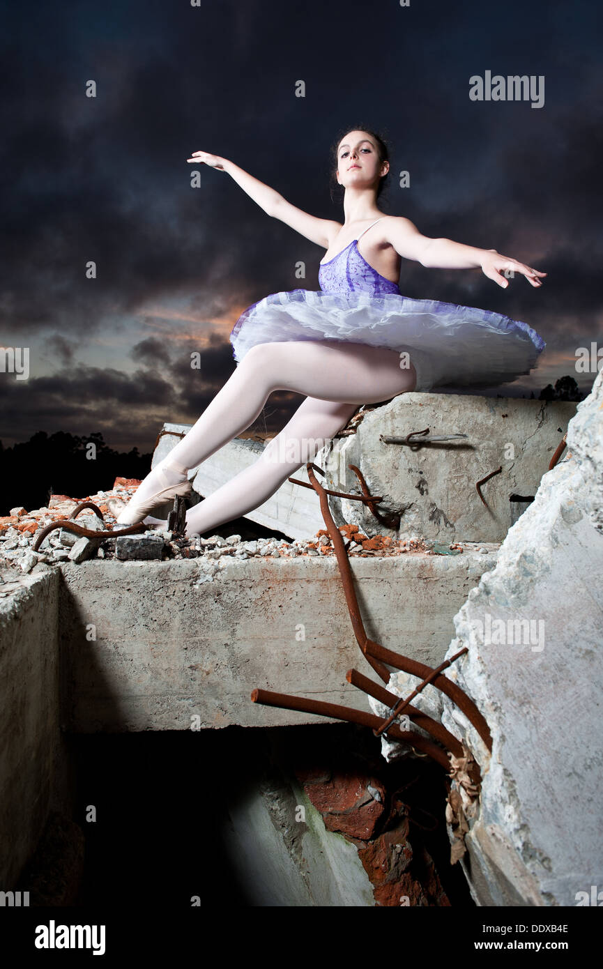 Ballerina posiert in einem alten verfallenen Gebäude während der letzten Stunde des Sonnenlichts und wenn die Sonne untergeht. Stockfoto