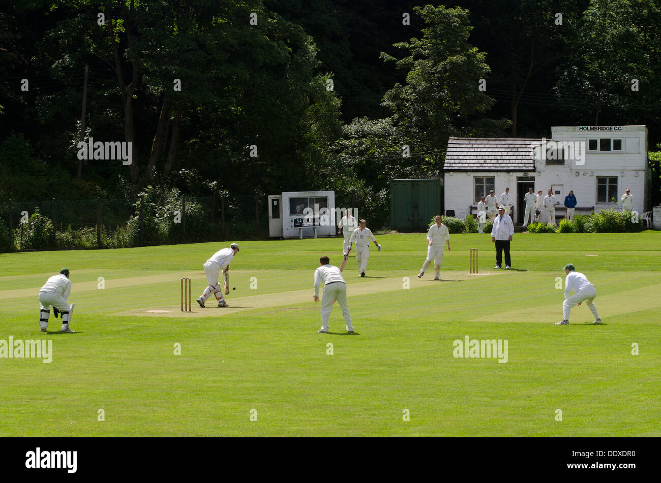 Dorf-Cricket-Szene im Holmbridge Cricket Club in West Yorkshire zeigt das Clubhaus im Hintergrund Stockfoto
