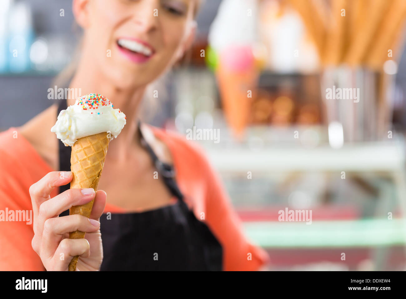 Junge Verkäuferin in einer Eisdiele mit Eis Kornett Stockfoto