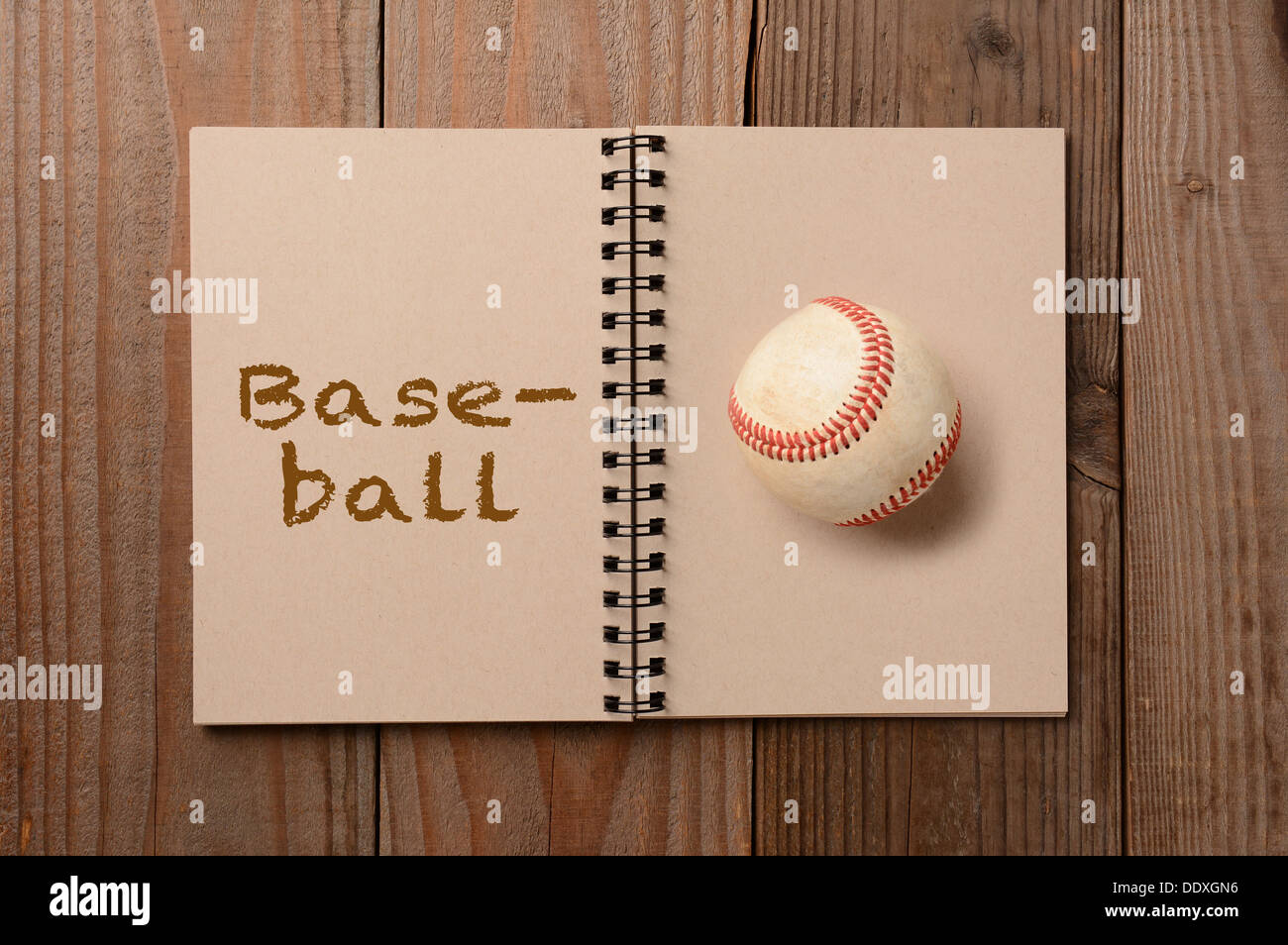 Ein abgenutzter Baseball auf die leere Seite eines Notebooks. Der gegenüberliegende Seite ist das Wort, das Baseball ausgeschrieben. Stockfoto