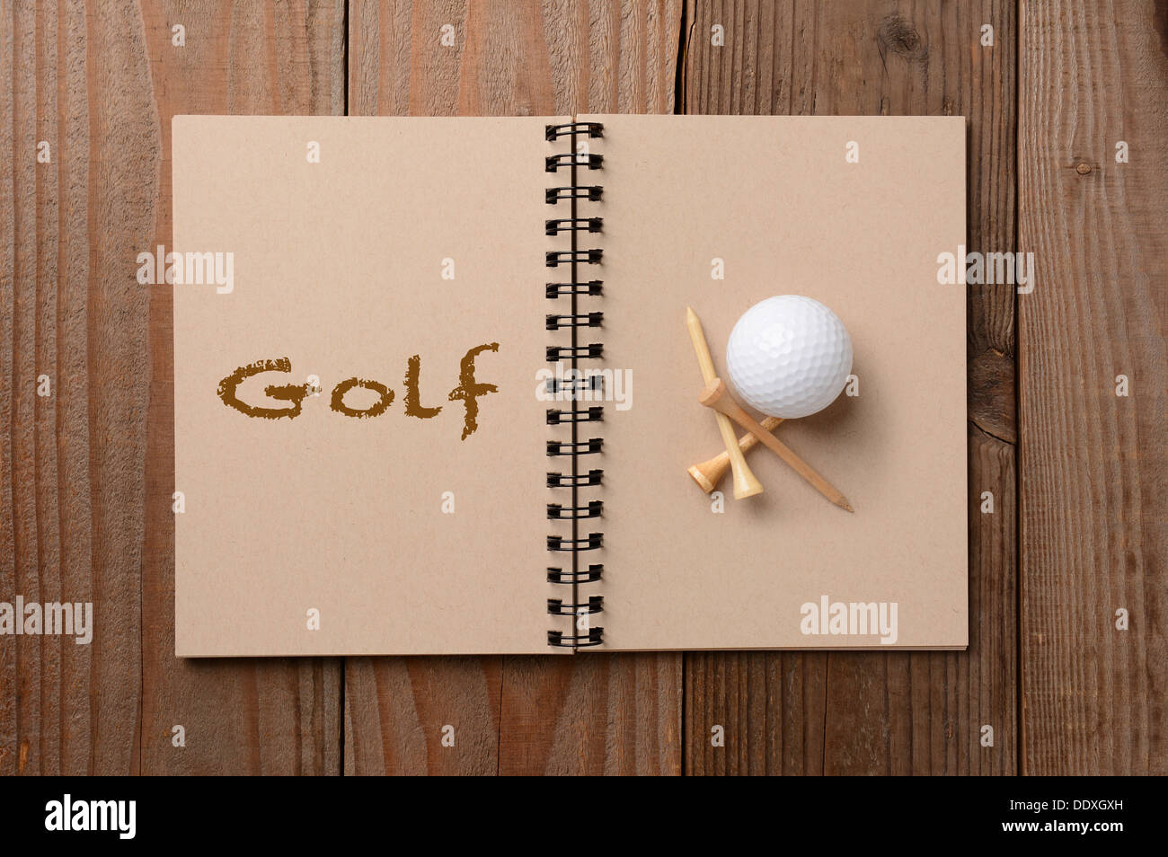 Ein Golfball und Tees auf die leere Seite eines Notebooks. Der gegenüberliegende Seite ist das Wort, das Golf ausgeschrieben. Stockfoto