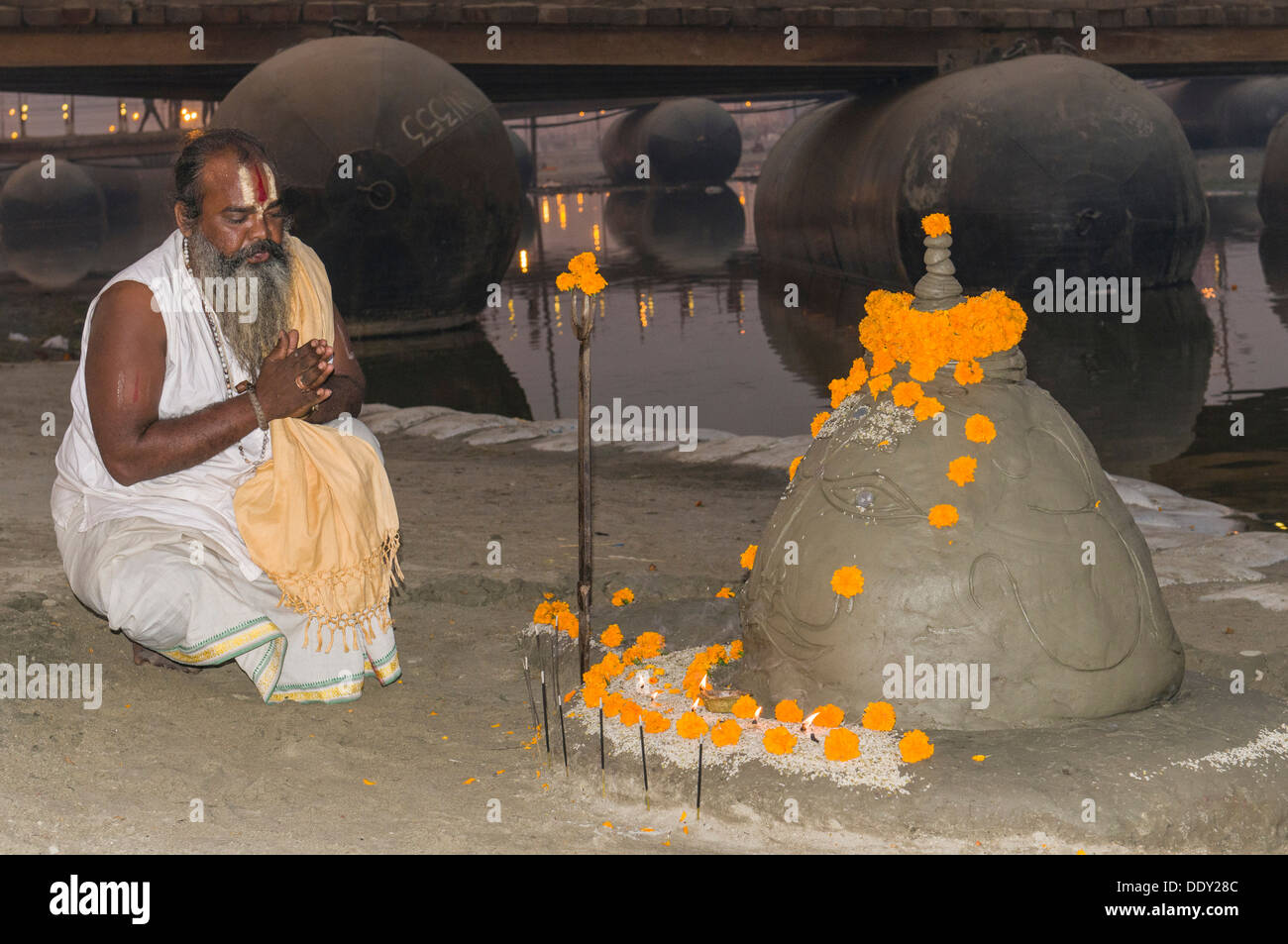 Priester, die an ein Shiva-Idol gemacht von Sand an der Sangam, dem Zusammenfluss der Flüsse Ganges und Yamuna Saraswati beten Stockfoto