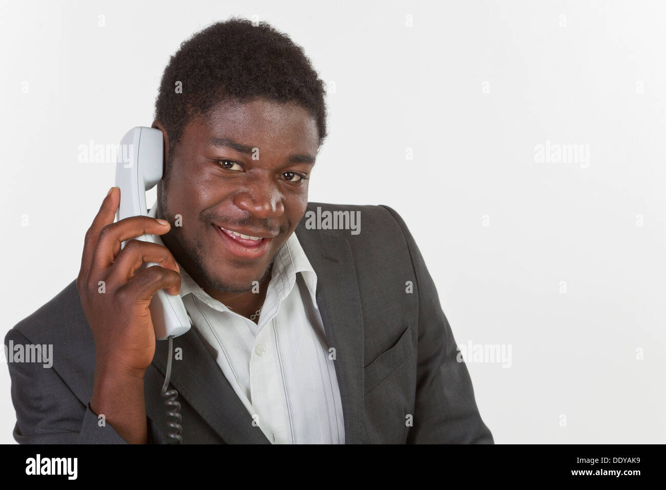 Junge schwarze Mann in einem Anzug, einen Anruf zu tätigen, in einem Büro, Lächeln Stockfoto
