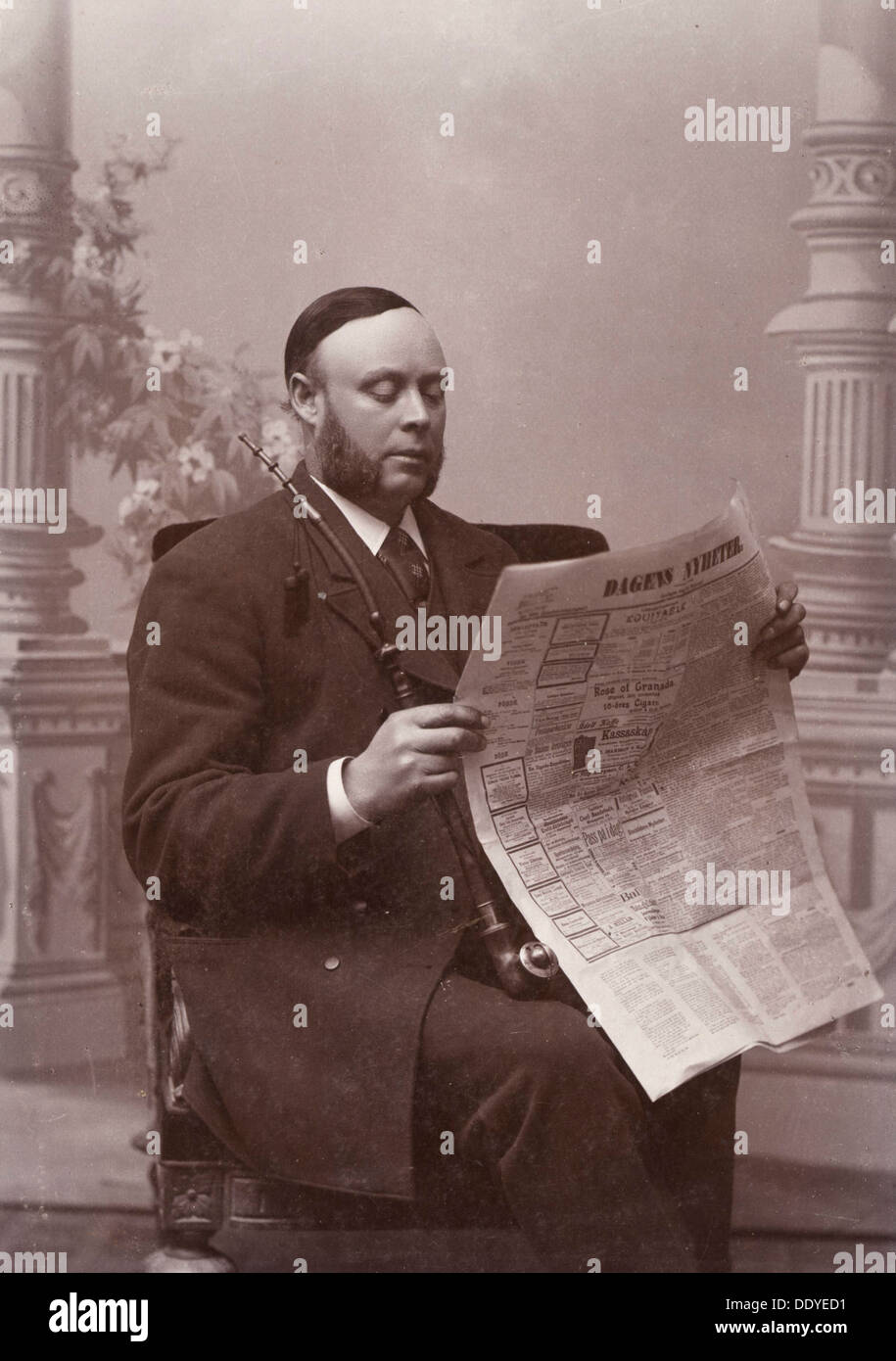 Mann eine Zeitung lesen mit einem langen Rohr in der Hand, Landskrona, Schweden, 1910. Artist: Unbekannt Stockfoto