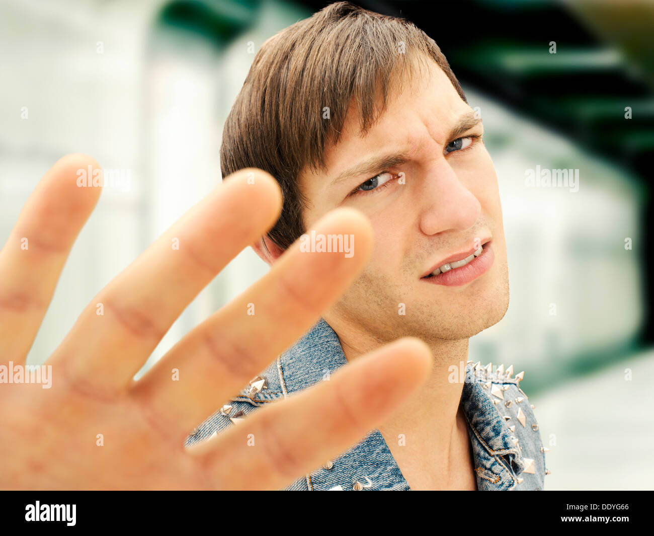 Junger Mann mit einem ernsten Gesicht trägt eine Jeansjacke Nieten, defensive Geste, portrait Stockfoto