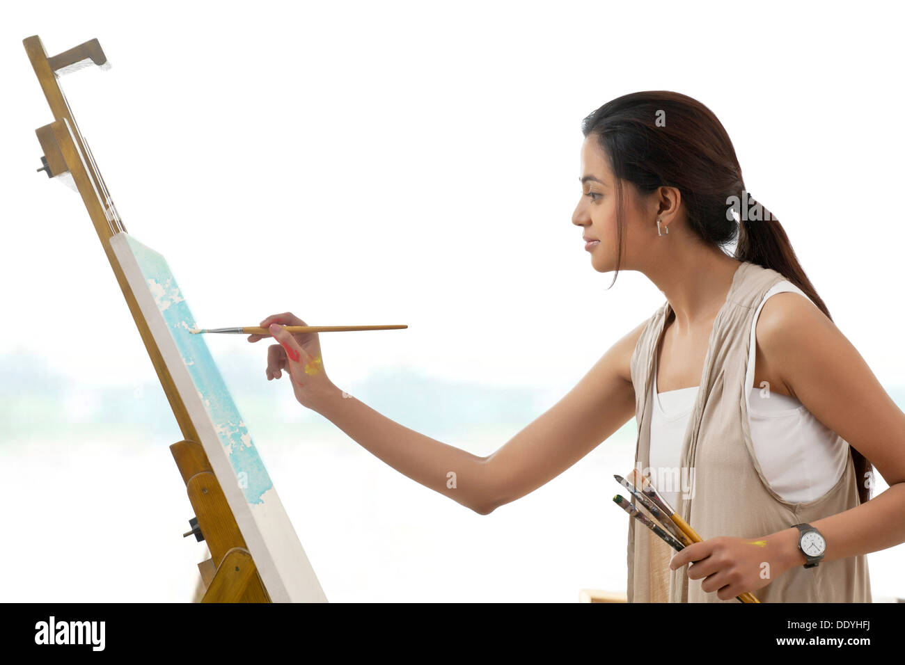 Seitenansicht der jungen Künstlerin Malerei auf Leinwand isoliert auf weißem Hintergrund Stockfoto