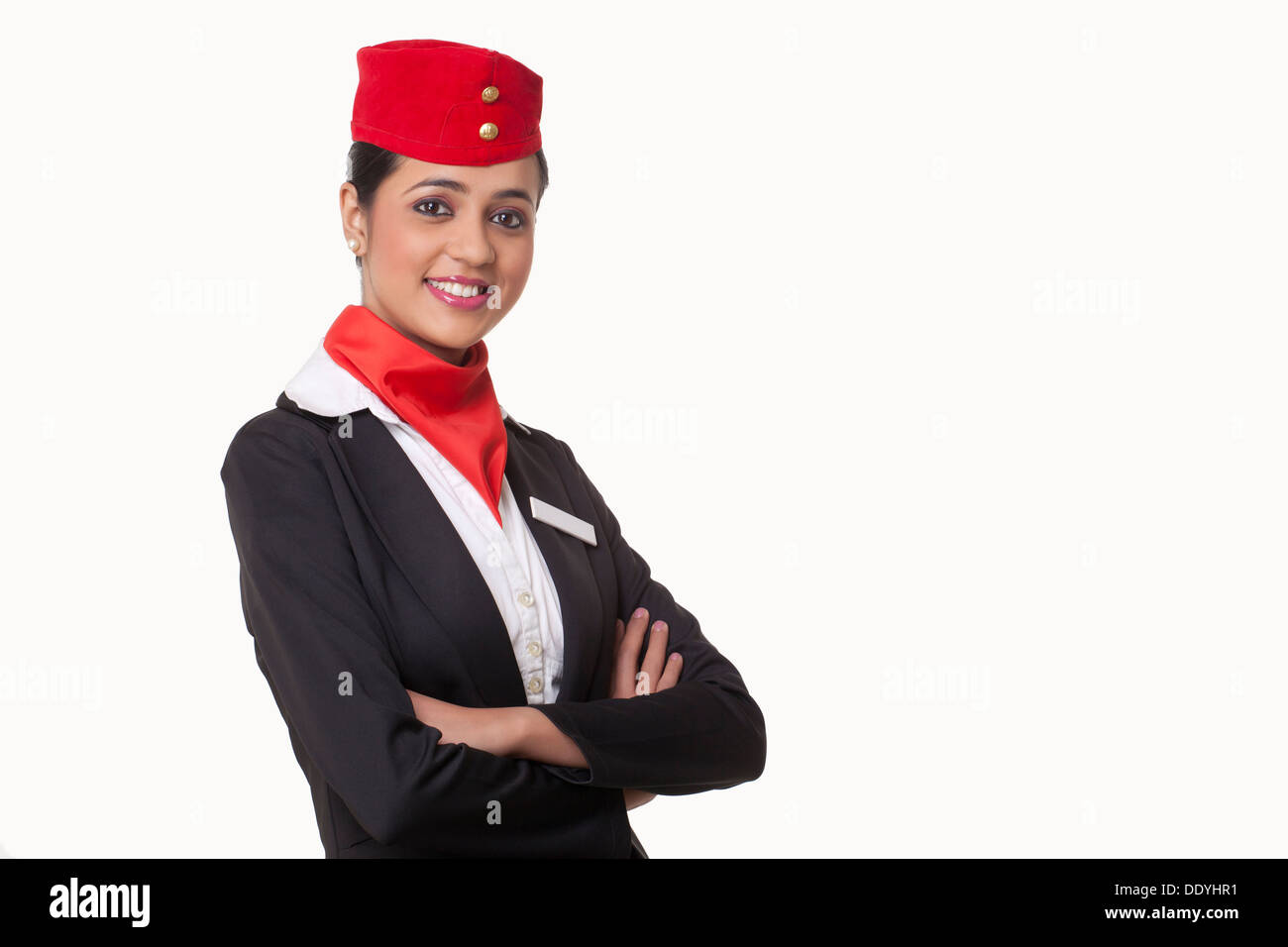 Porträt des jungen Stewardess mit verschränkten Armen vor weißem Hintergrund stehen Stockfoto