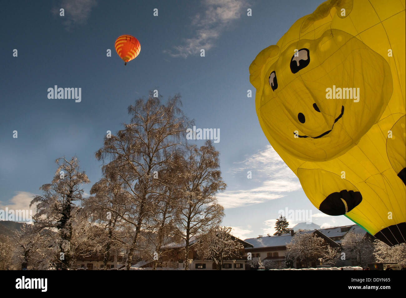 Roten Heißluftballon vor blauem Himmel, gelb Heißluft-Ballon in der Form eines lächelnden Gesichtes wird aufgeblasen, 12. Reisen Stockfoto