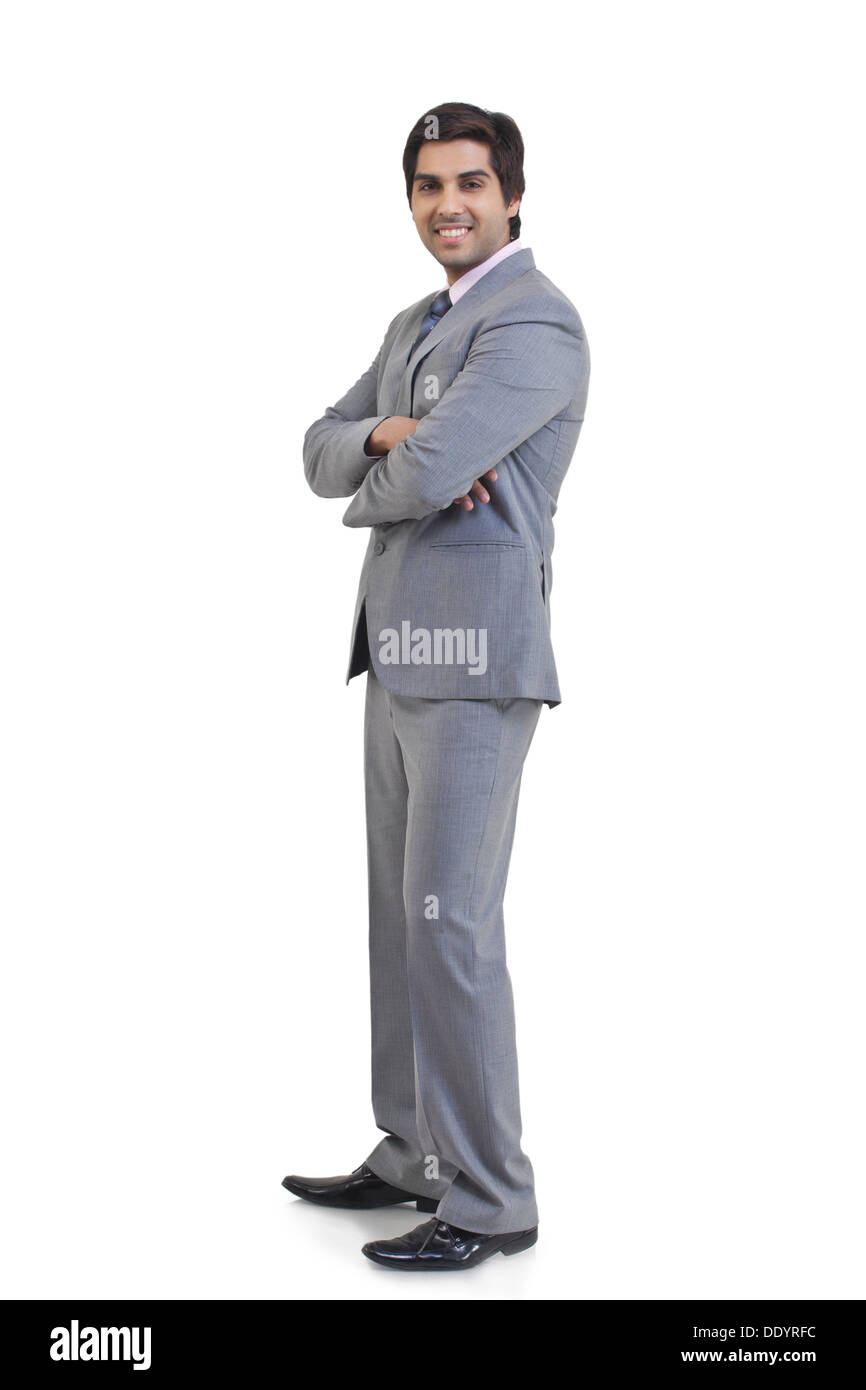 In voller Länge Portrait von junger Geschäftsmann mit Arme gekreuzt stehend vor weißem Hintergrund Stockfoto
