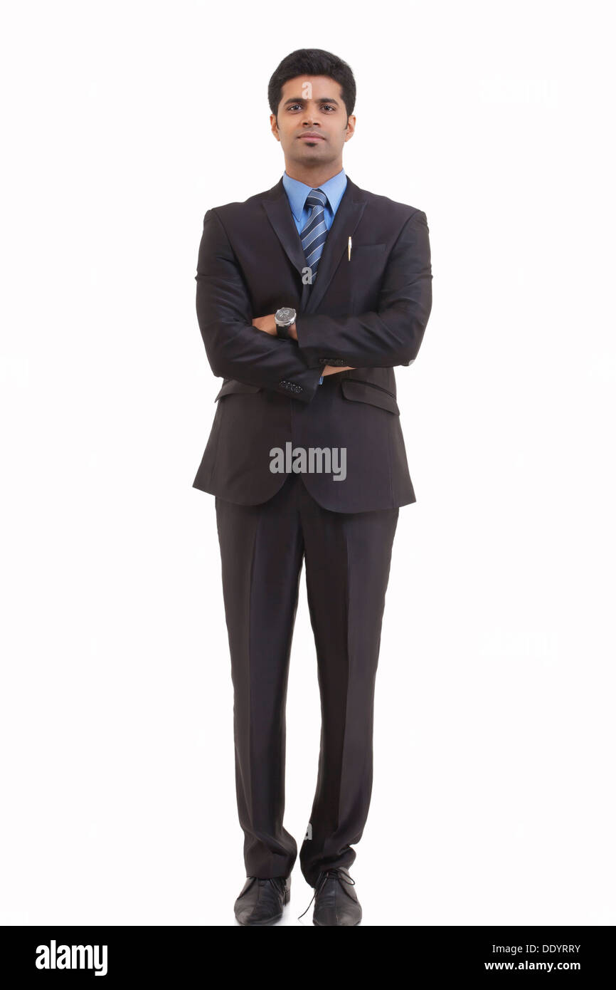 In voller Länge Portrait von junger Geschäftsmann mit Arme gekreuzt stehend vor weißem Hintergrund Stockfoto