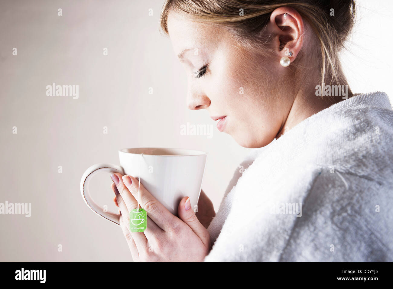 Junge Frau, eine Tasse Tee in der Hand halten und entspannen Stockfoto