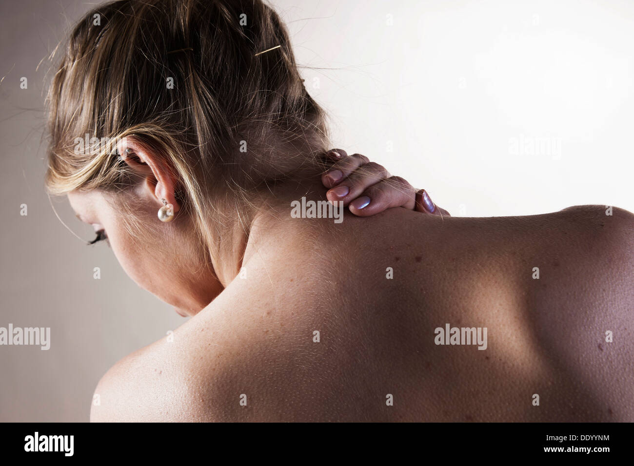 Junge Frau mit Nackenschmerzen, Ansicht von hinten Stockfoto
