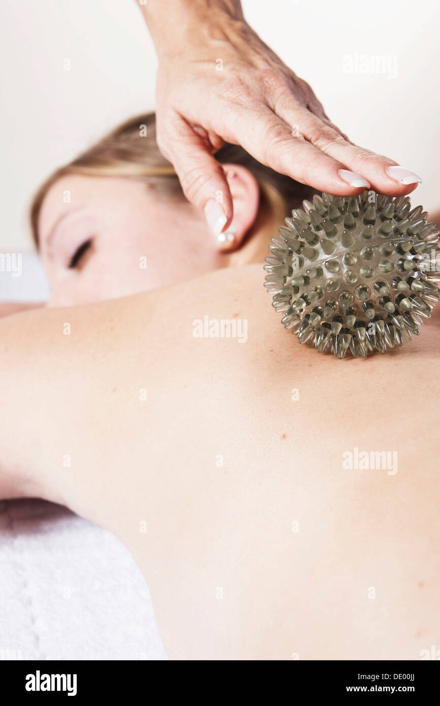 Junge Frau massiert auf der Rückseite mit einem spikey Gummiball-massage Stockfoto
