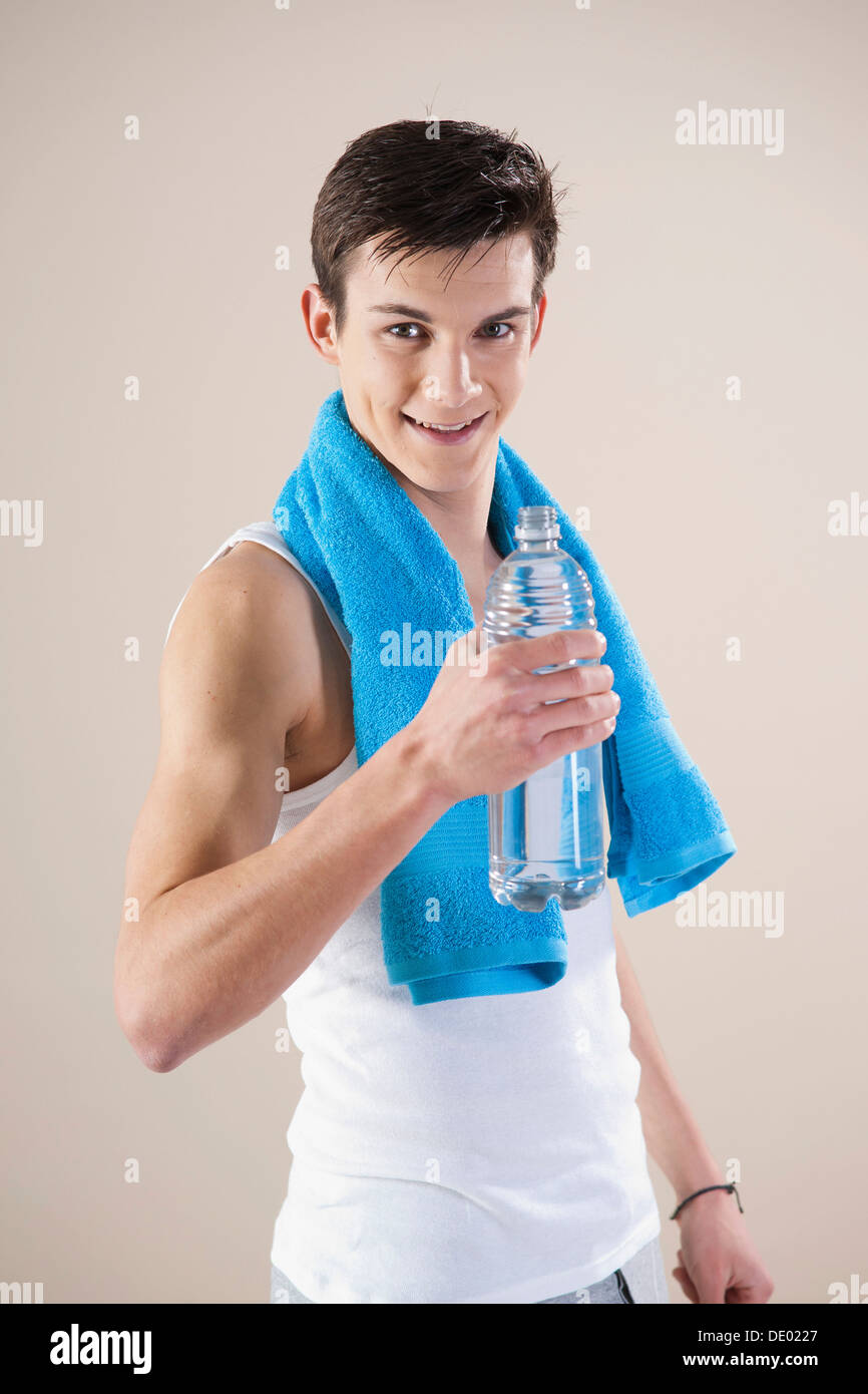 Lächelnder junge Mann nach dem Sport mit einer Wasserflasche in der hand Stockfoto