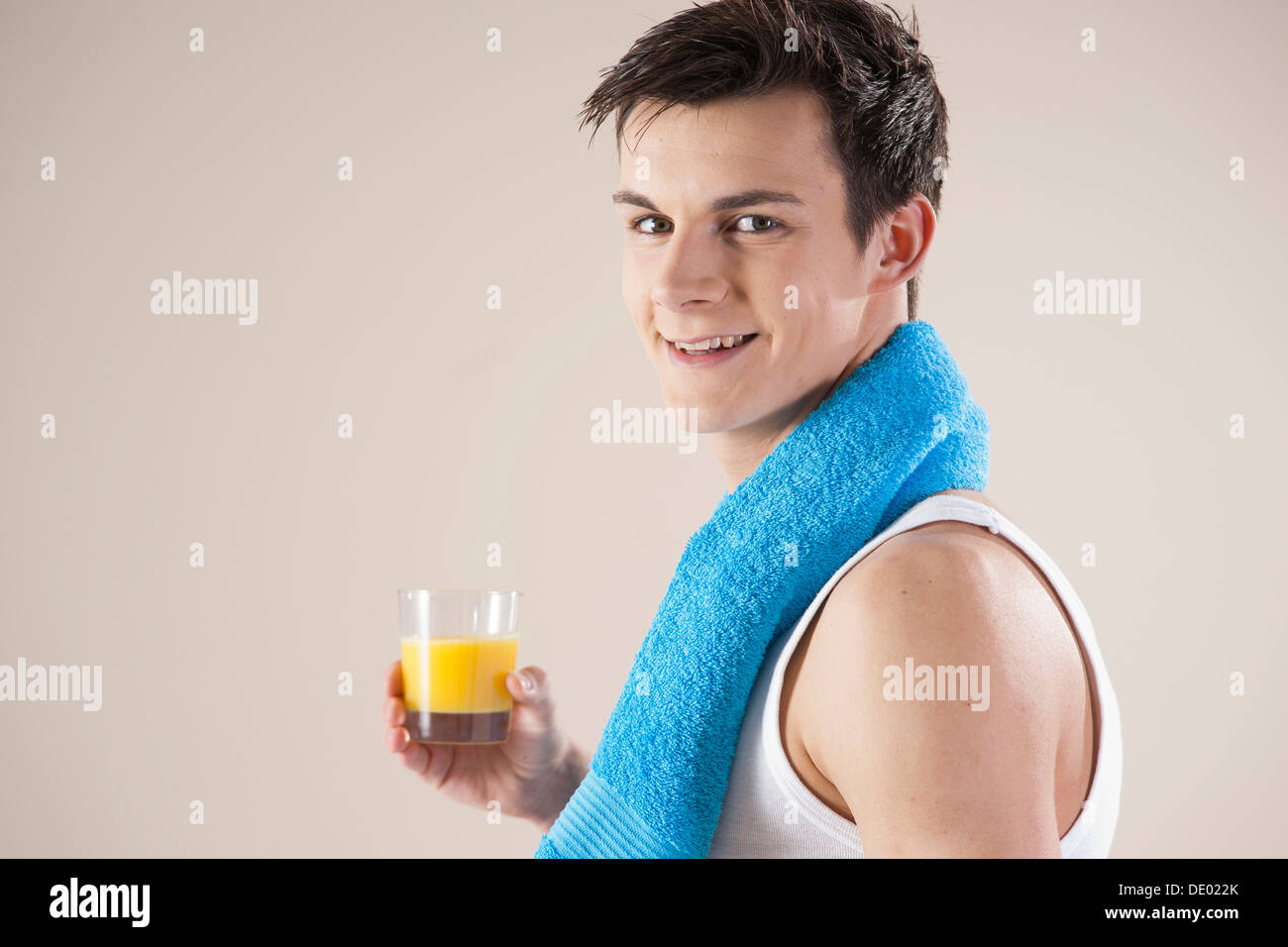 Lächelnder junge Mann nach dem Sport mit einem Glas Saft in der hand Stockfoto