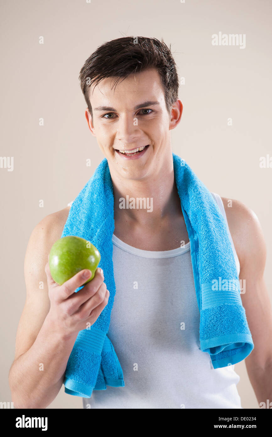 Lächelnder junge Mann nach dem Sport mit einem Apfel in der hand Stockfoto
