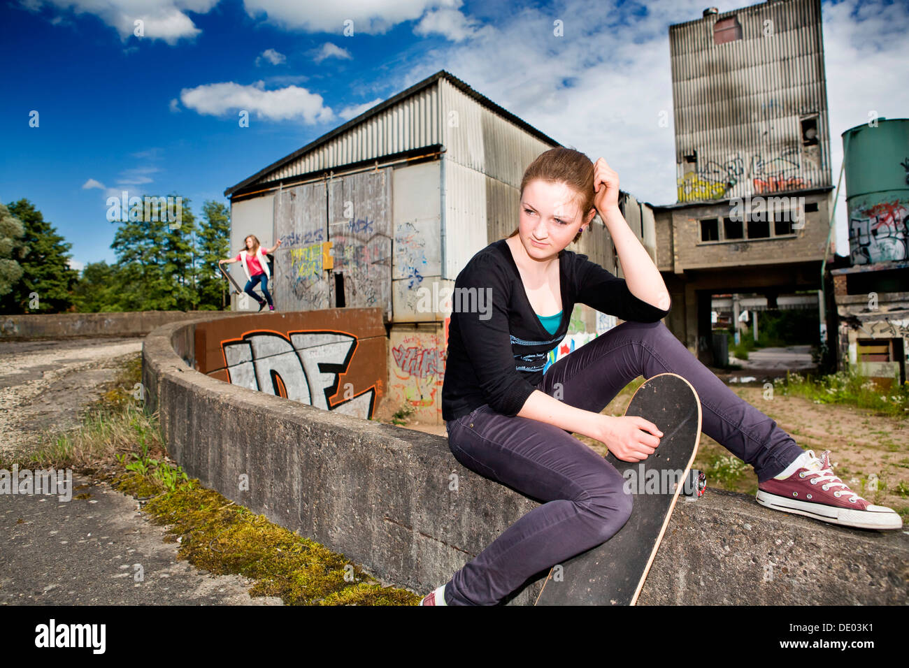 Porträt eines jungen Mädchens mit einem Skateboard sitzt in einem städtischen Gebiet Stockfoto