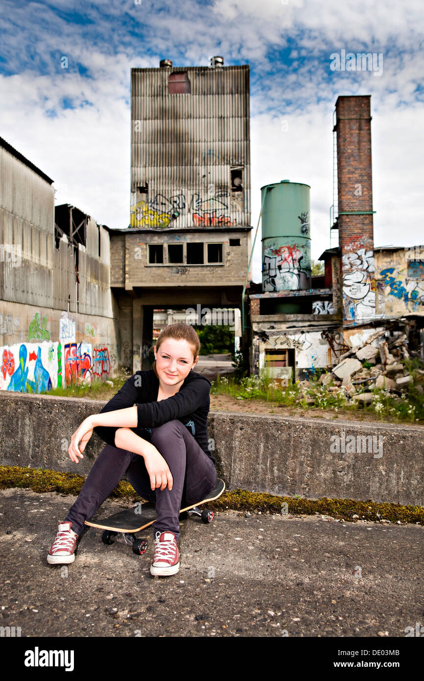 Porträt eines jungen Mädchens sitzen auf einem Skateboard in einem städtischen Gebiet Stockfoto