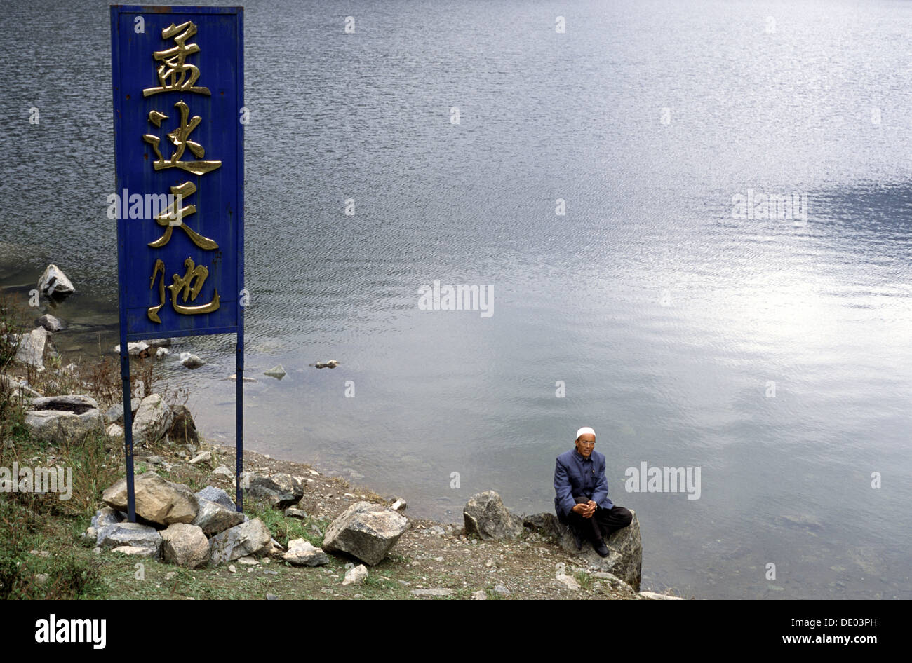 Ein Chinese sitzt am Ufer des Himmlischen Sees oder Tianchi im Qinghai Mengda National Nature Reserve Mengda ziran baohuqu südöstlich von Xining in der Autonomen Präfektur Xunhua Sala, China Stockfoto Ein Chinese sitzt am Ufer des Himmlischen Sees oder Tianchi im Qinghai Mengda National Nature Reserve Mengda ziran baohuqu südöstlich von Xining in der Autonomen Präfektur Xunhua Sala, China Stockfoto