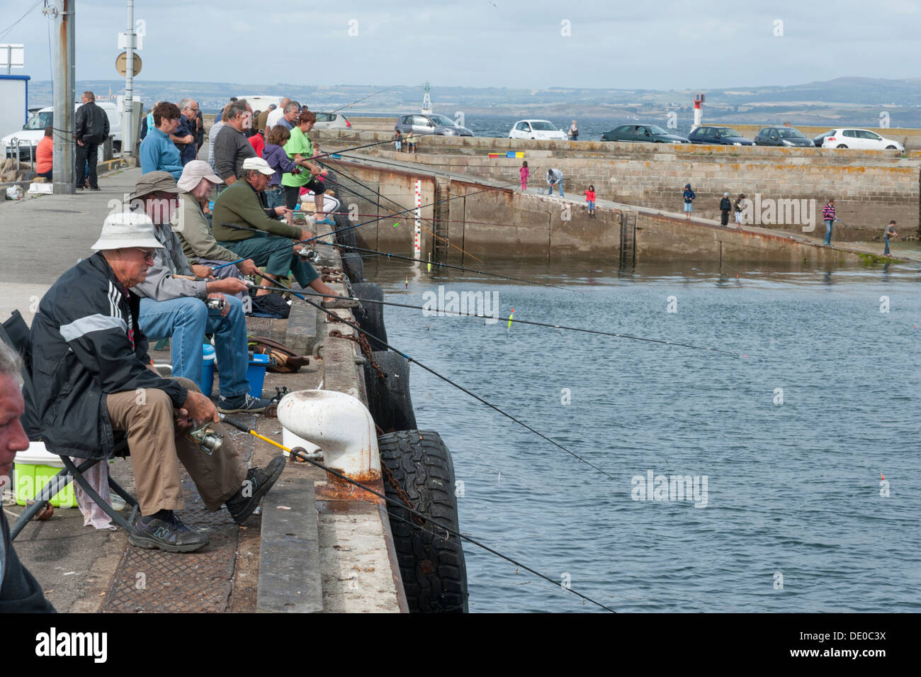 Viele Menschen, die Angeln mit Rute und Schnur an der Hafenmauer Douarnenez Brittany France Stockfoto