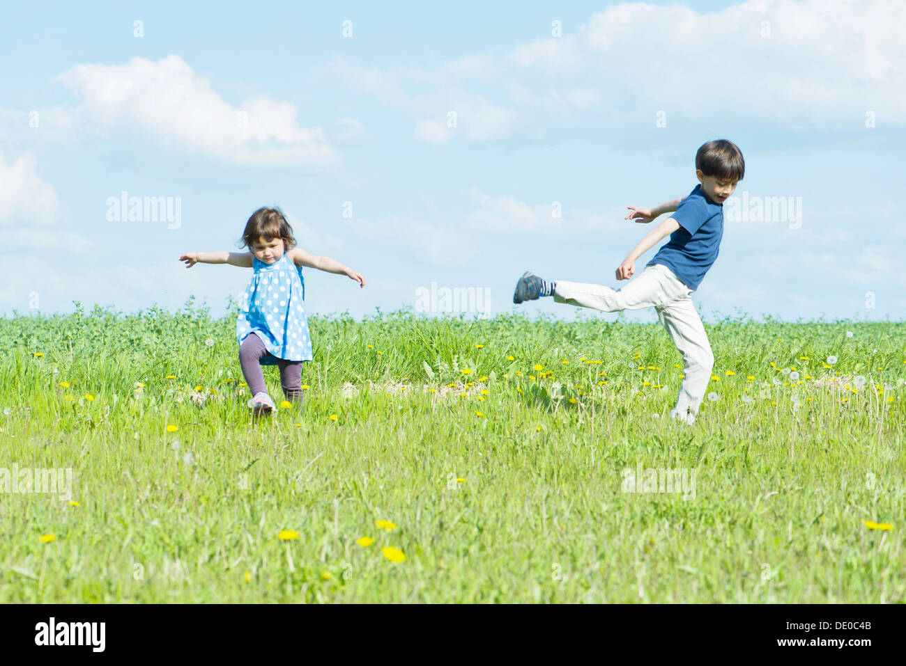Kinder laufen im Feld mit Armen Stockfoto