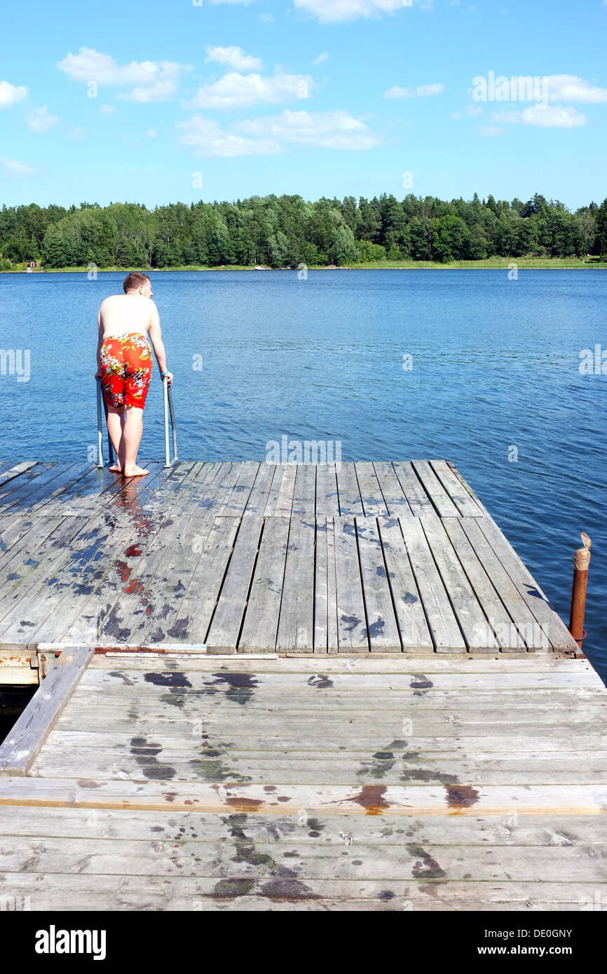 Ein Schwimmer steht auf einem Holzsteg, der Blick auf die Ostsee in Schweden. Stockfoto