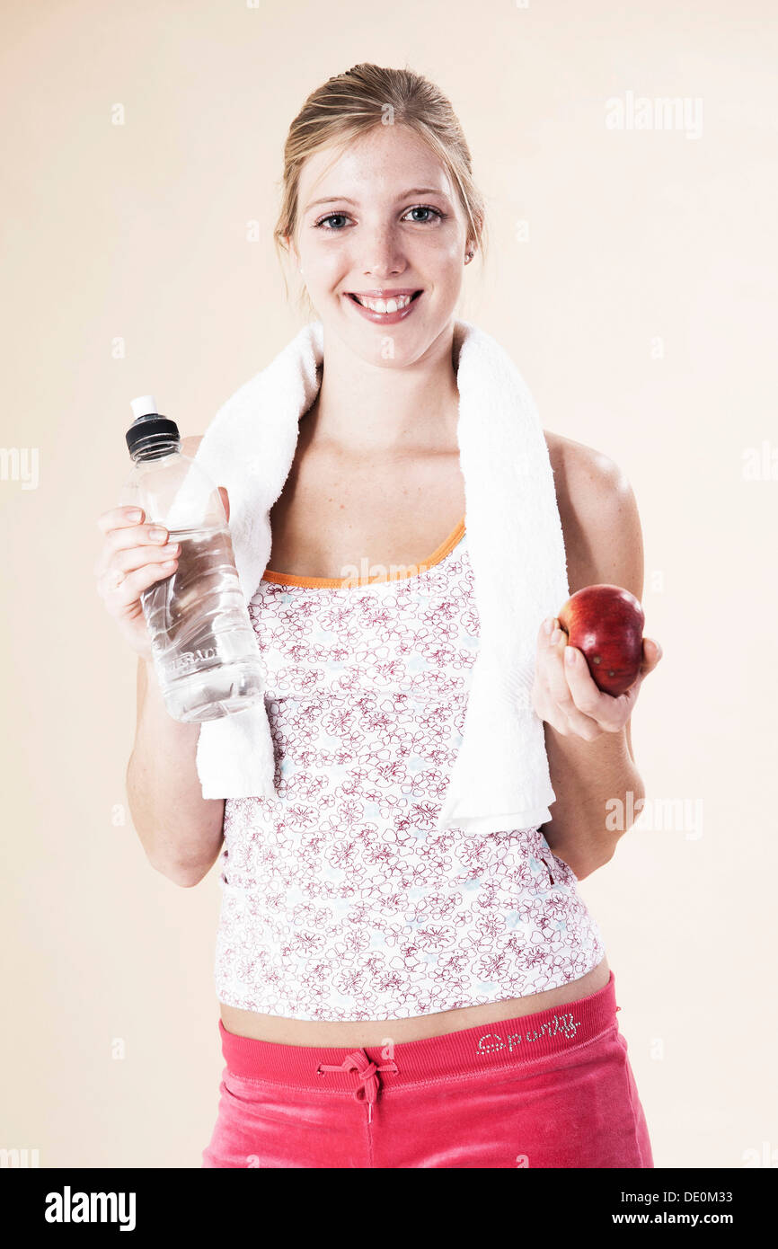 Junge Frau nach dem Training hält einen Apfel und eine Flasche Wasser Stockfoto