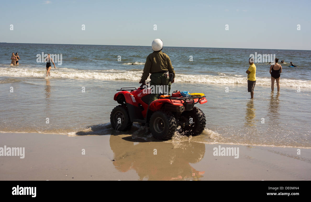 Ein NY Dept. of Parks Enforcement Officer leitet die Menschen aus dem Wasser in Rockaway Beach Stockfoto