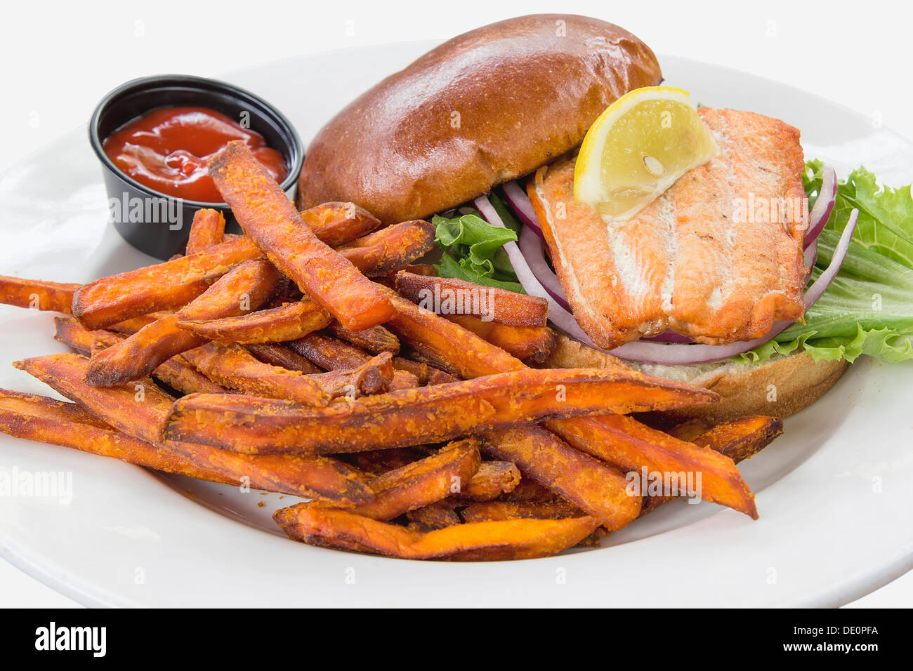 Lachs Fisch Steak Sandwich mit Zwiebel-Tomaten-Salat und Süßkartoffel-Pommes frites Stockfoto