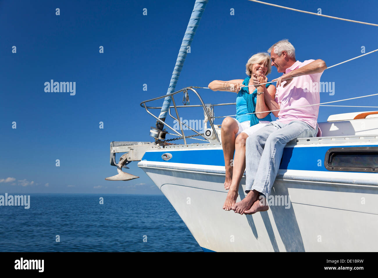 Ein senior Brautpaar halten Hände, lachende sitzend auf einem Segelschiff auf eine ruhige blaue Meer Stockfoto