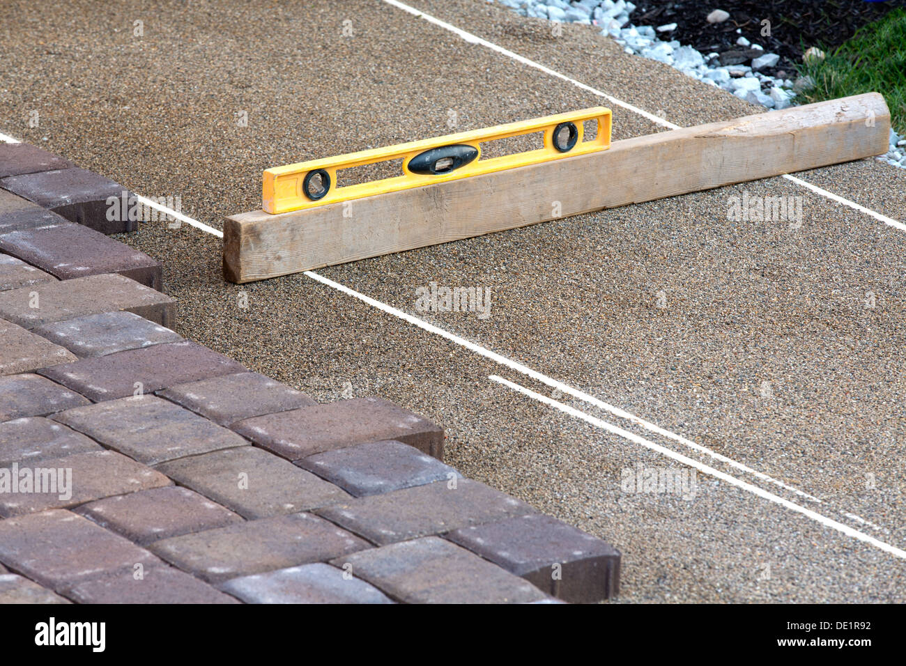 Pflaster Arbeit erledigt, kostbar Nivellierung des Sandes mit gelben und Stück Holz Stockfoto