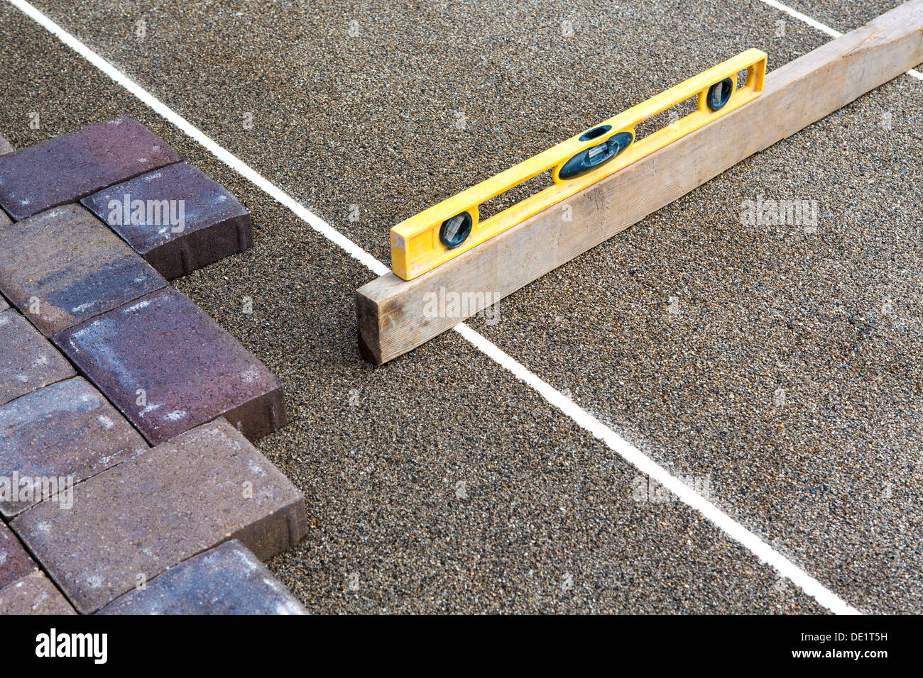 Pflaster Arbeit erledigt, kostbar Nivellierung des Sandes mit gelben und Stück Holz Stockfoto