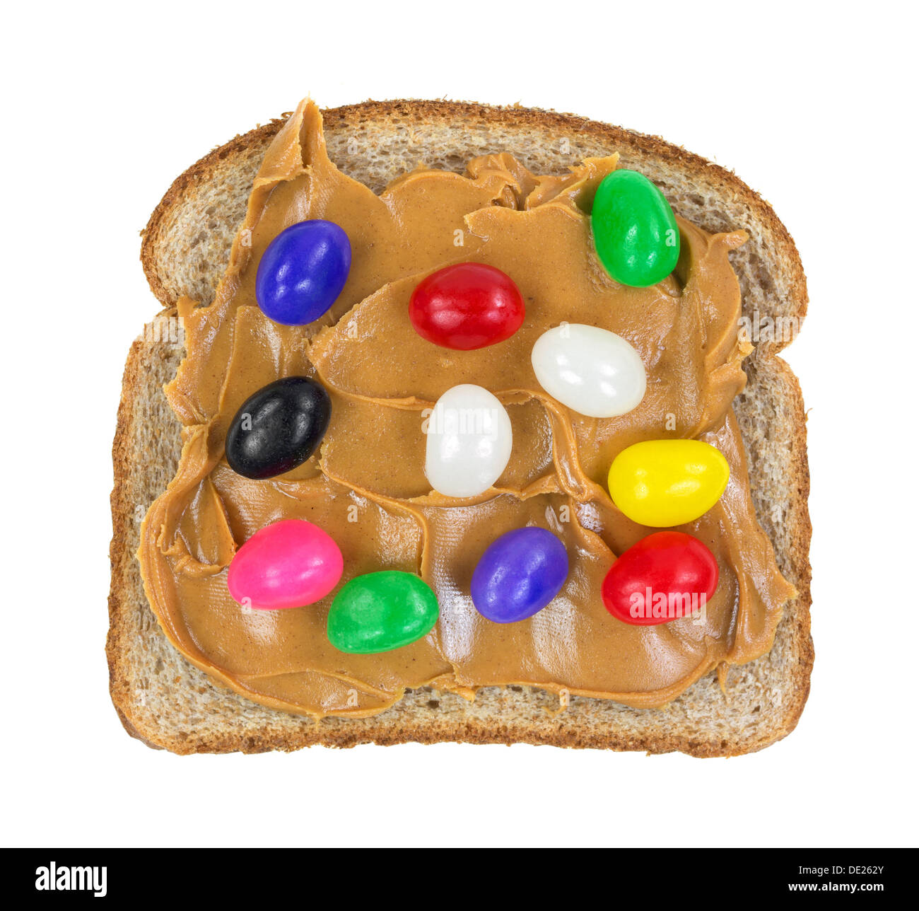 Eine Scheibe Vollkornbrot mit Erdnussbutter und Gummibärchen auf weißem Hintergrund. Stockfoto