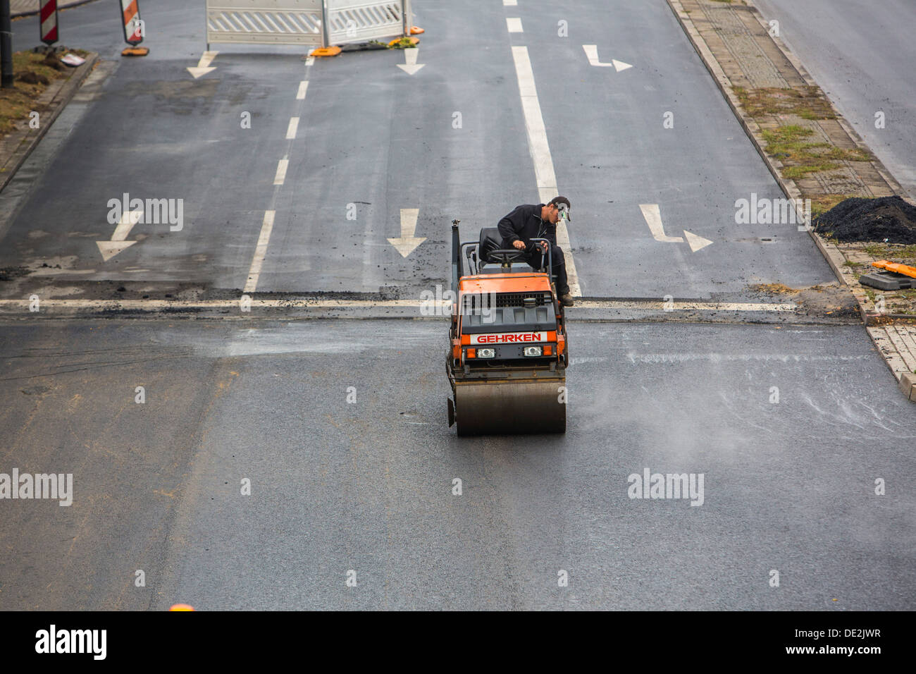 Innerstädtische Straßenbaustelle. Asphaltierte Arbeit an einer großen Straßenkreuzung. Neue Asphaltdecke. Alfred Str., B224 in Essen. Stockfoto