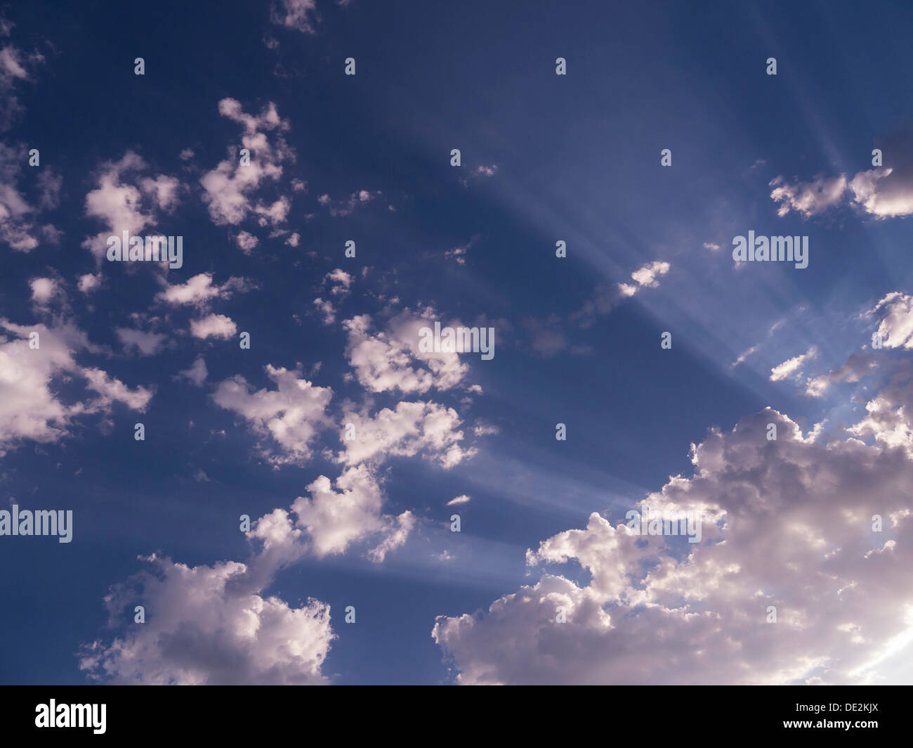 Blauer Himmel mit weißen flauschigen Wolken und strahlende Sonnenstrahlen. Stockfoto