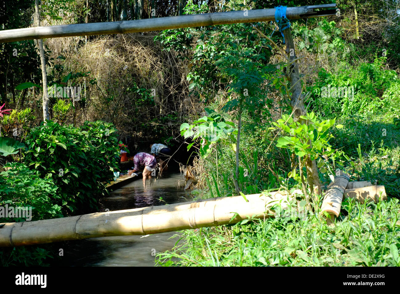 lokale Dorffrauen hinter Bambus-Brücke, die ihre Wäsche im Fluss Java Indonesien Stockfoto