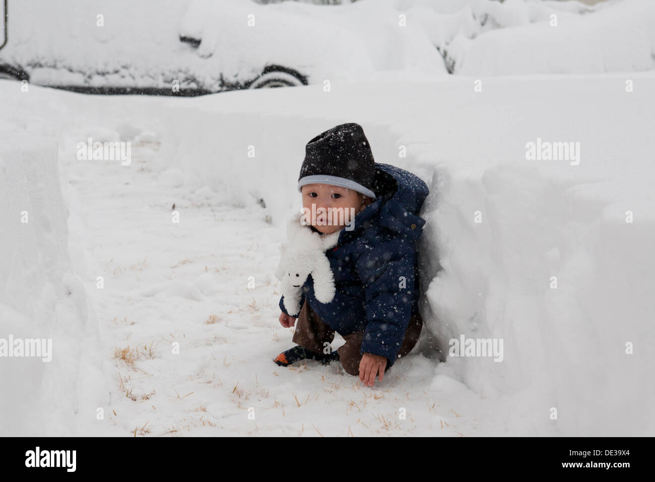 Asiatisches Baby Junge sitzt auf Schnee Stockfoto
