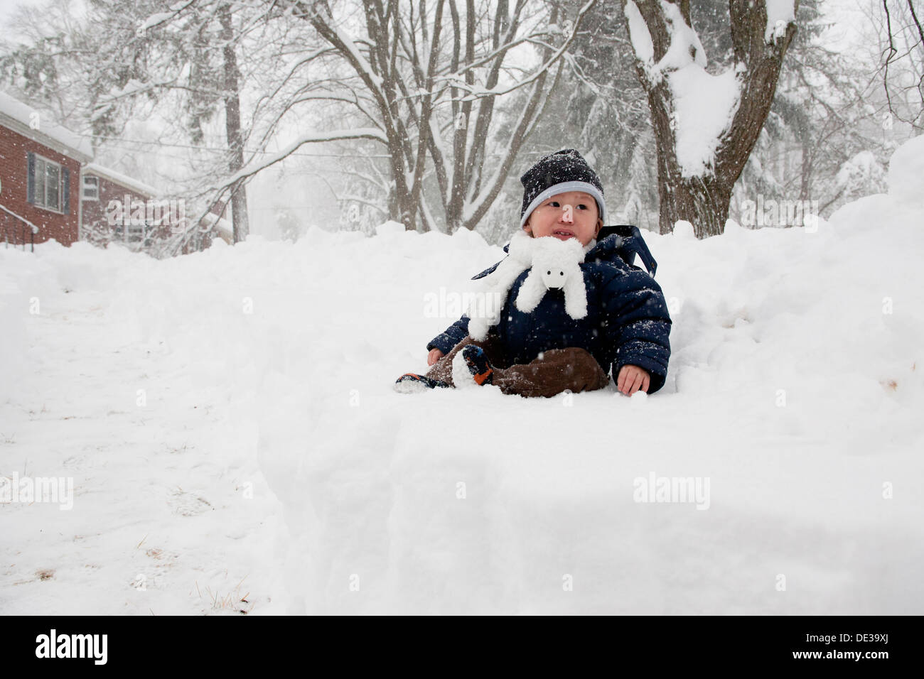 Asiatisches Baby Junge sitzt auf Schnee Stockfoto