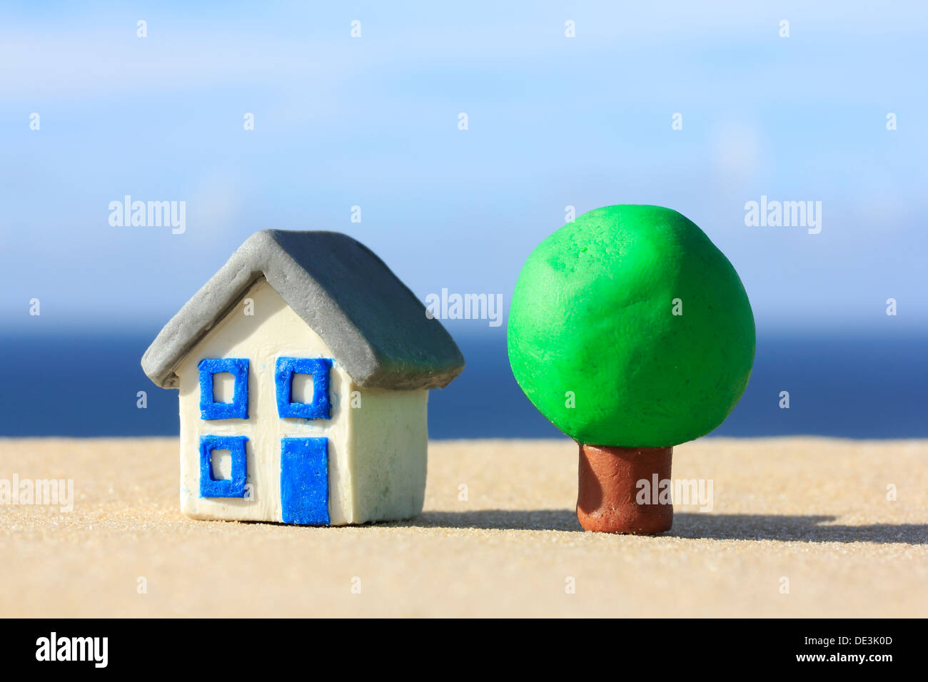 Plastilin Haus und Baum auf Sand an der Küste Stockfoto