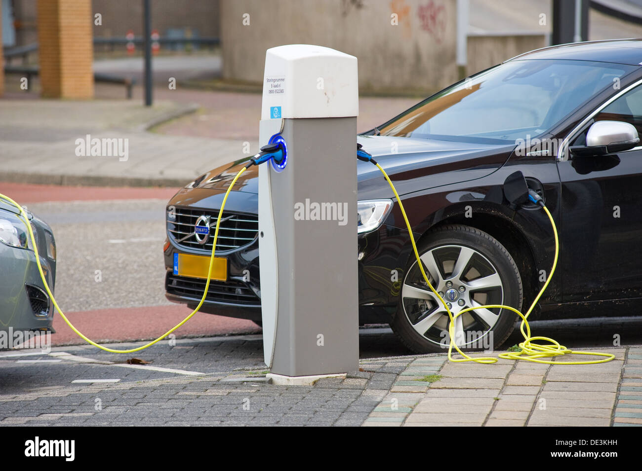 Zwei Elektroautos sind auf einen Parkplatz im Zentrum der Stadt geparkt, während sie bei einem Kraftwerk wieder aufgeladen werden. Stockfoto